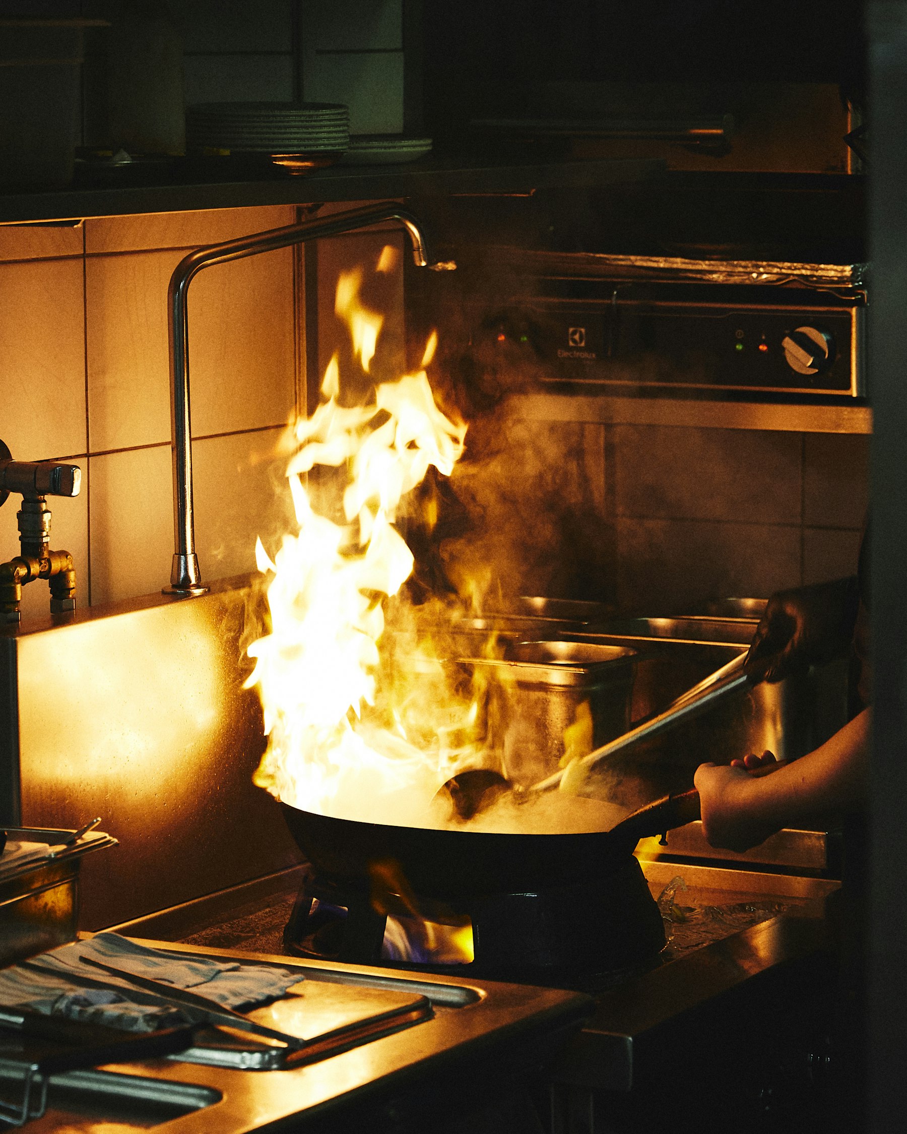 Flames rising from a pan on a professional stove